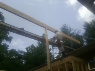 Carpenter setting a ridge beam over a new addition frame — Ice Dam Removal by Roofing Brothers in Andrew