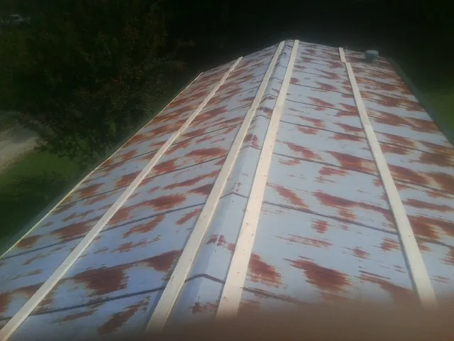 Rusted metal roof panels with new wood purlins before replacement — Storm Damage Roof Repair in Andrew by Roofing Brothers