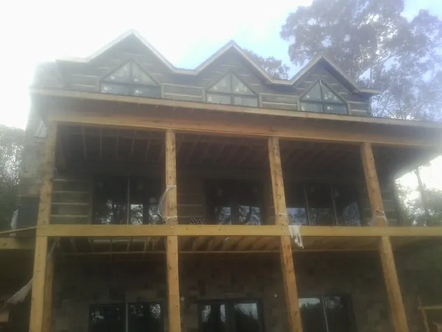 Dormers and porch framing on a large log home under construction — Roof Coating work by our crew in Andrew