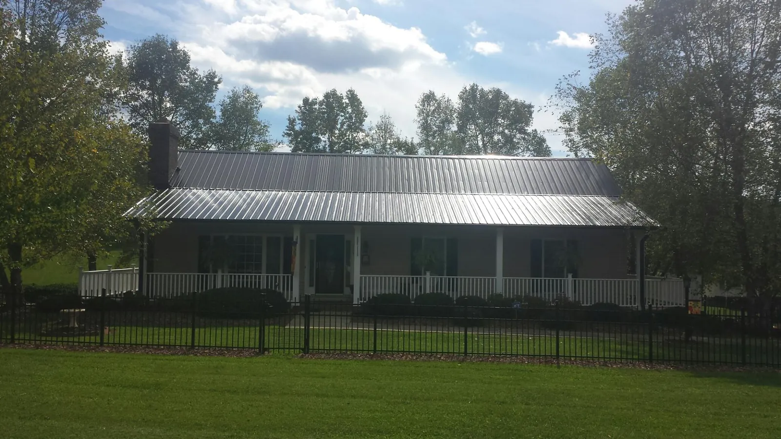 Gray metal roof on a brick ranch with a full width front porch — Gutter Guard Installation work by our crew in Andrew
