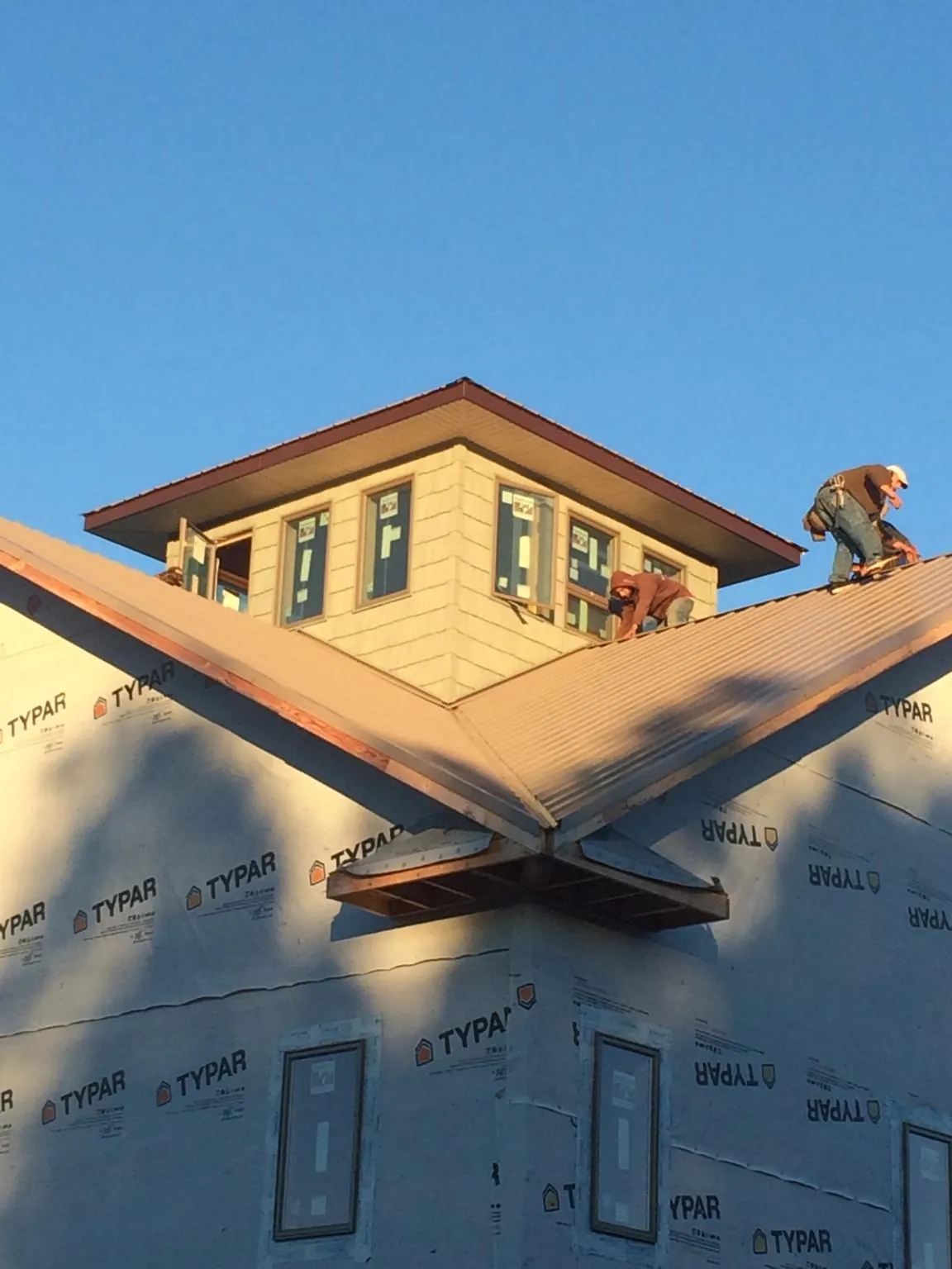 Roofers working around a rooftop cupola on a new metal roof at sunset — Roof Waterproofing in Andrew by Roofing Brothers